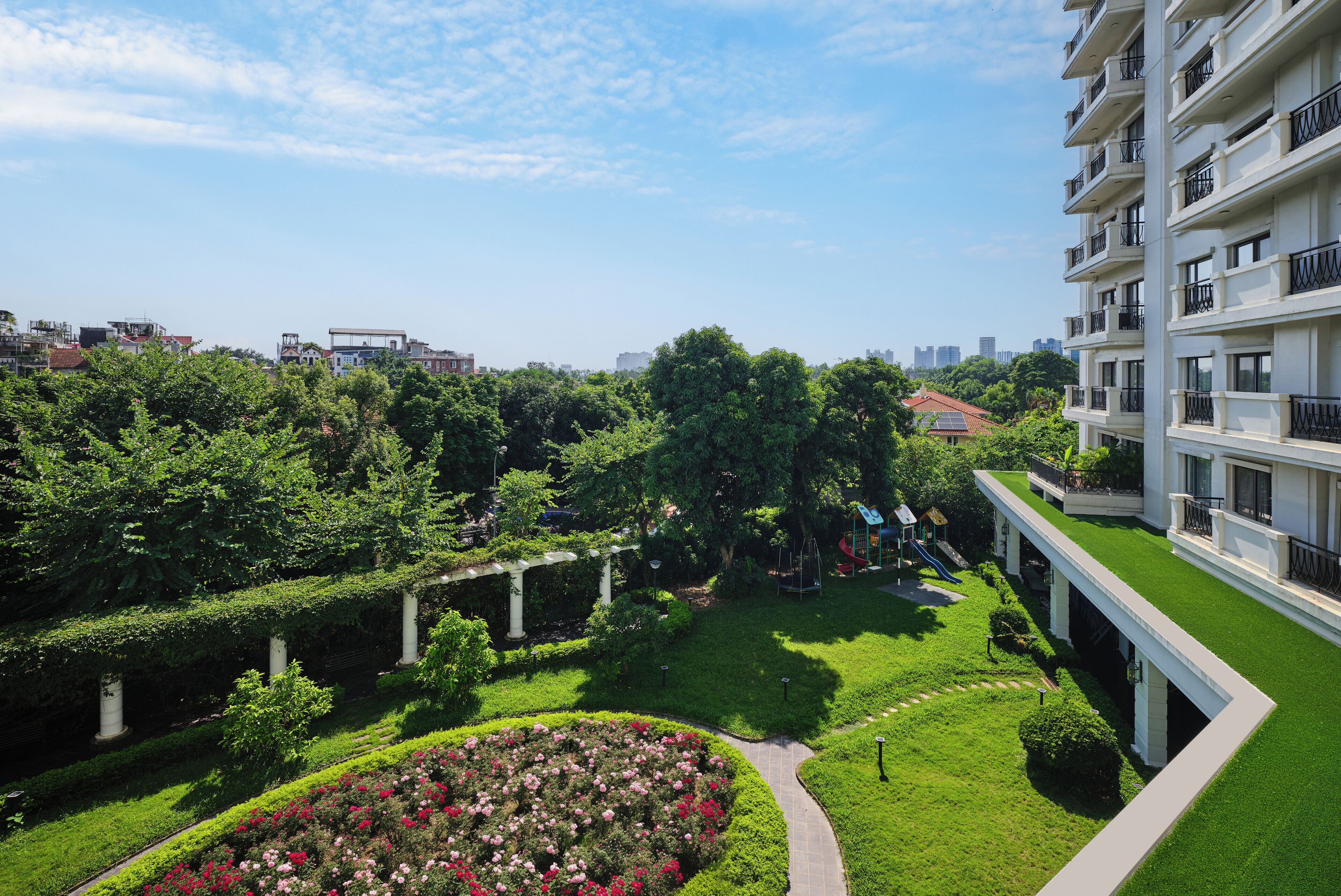 A residential area with a well-maintained garden, a pathway, and a multi-story building with balconies.