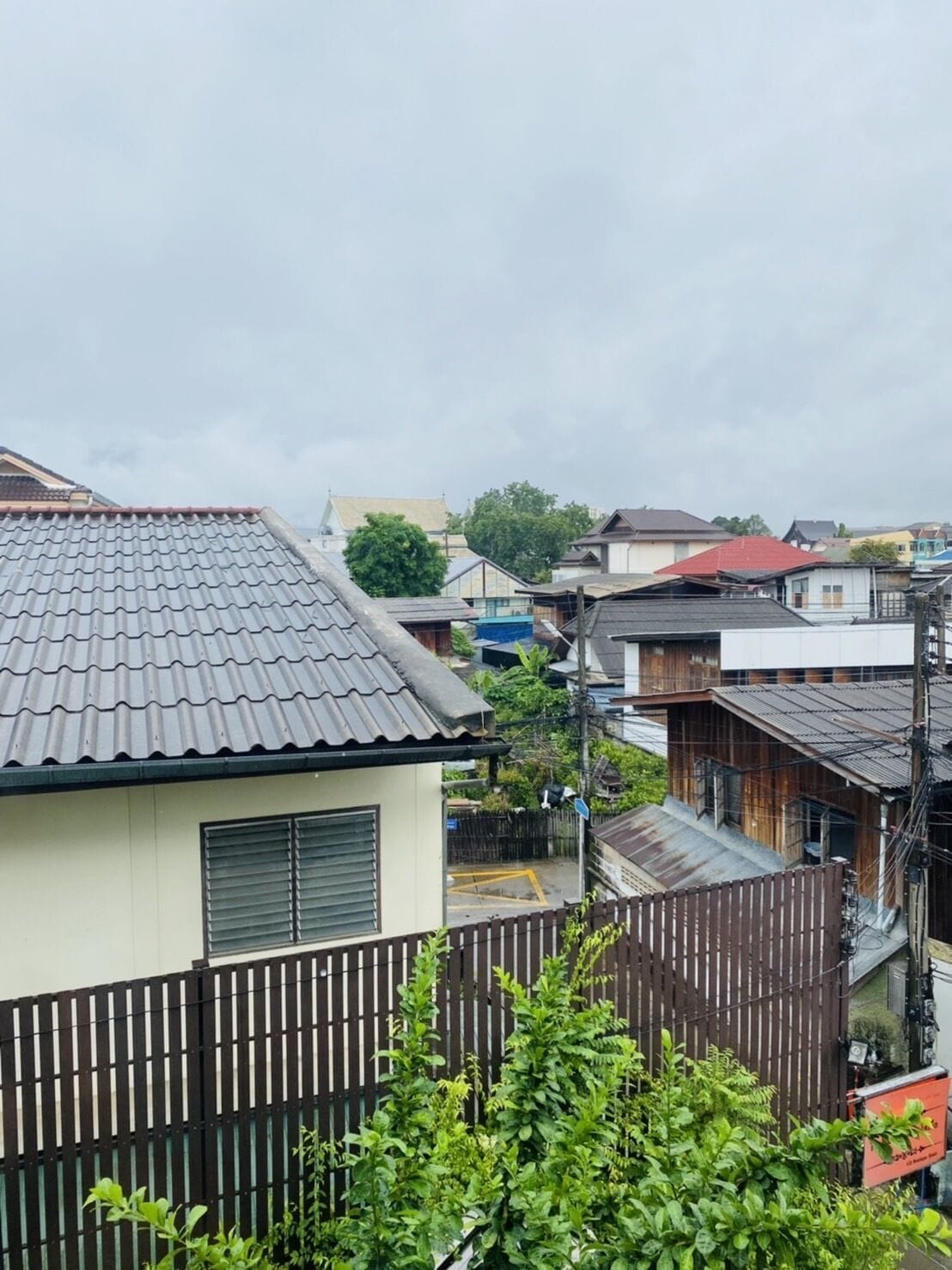 Un quartier résidentiel avec des maisons traditionnelles japonaises, une clôture en bois et une rue dont le marquage au sol est constitué d’une ligne jaune.