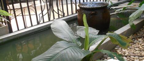 A courtyard with a water feature, a chair, and a potted plant.