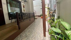 Un pasillo con suelo de baldosas, una escalera y plantas en macetas a lo largo de la pared.