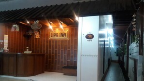 Zona de recepción de un hotel con interior de madera, mostrador de recepción y un cartel que dice 'LIFE INN'.