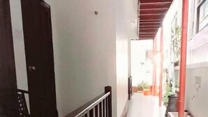 Un pasillo con barandilla de madera, una puerta y una planta en maceta.