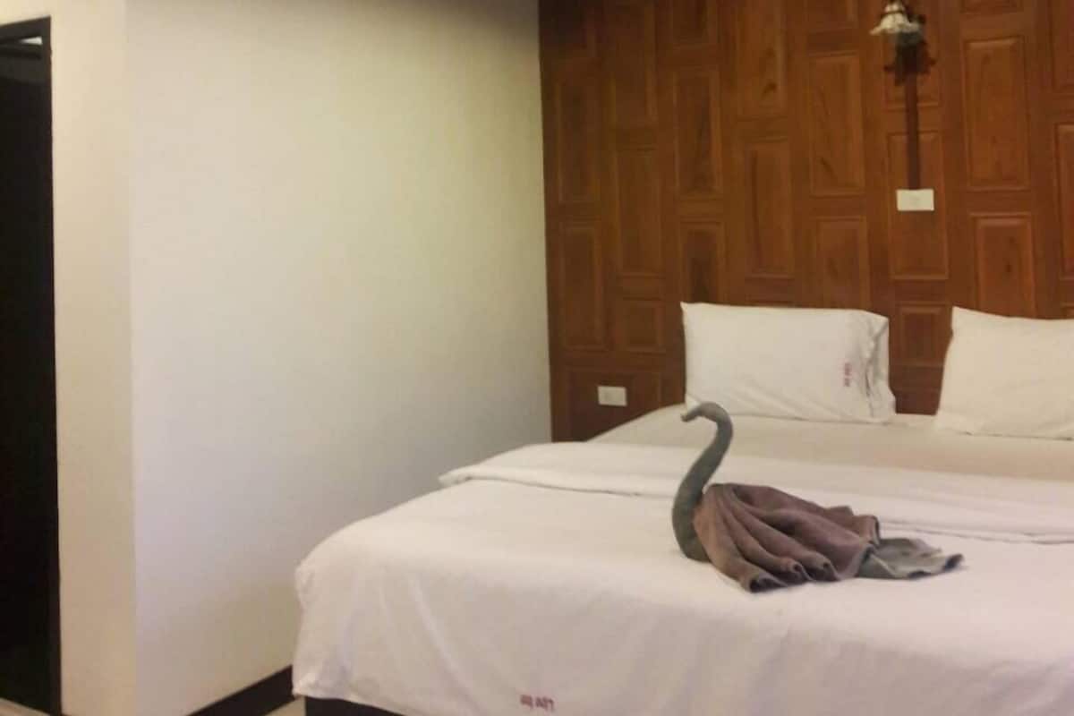 Une chambre d’hôtel avec un plafond en bois, un lit avec une literie blanche et un mur recouvert de panneaux de bois.