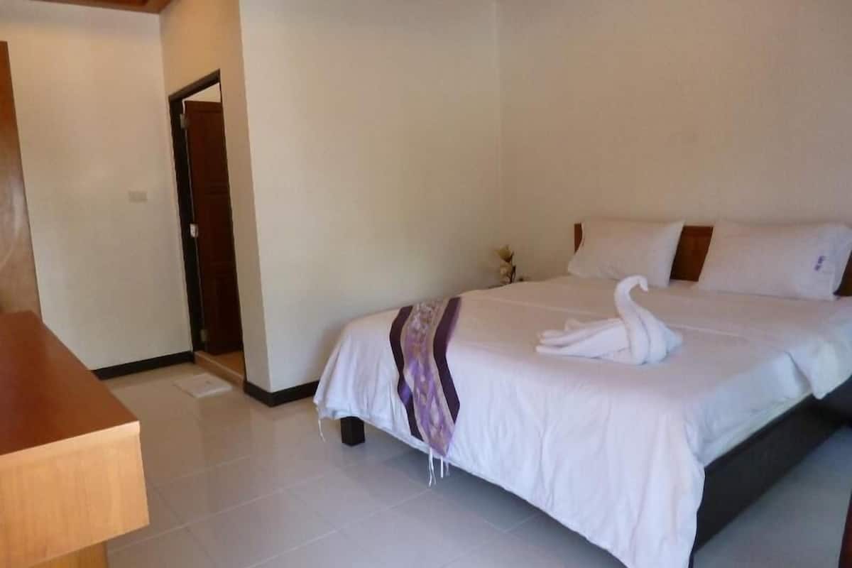 Une chambre d’hôtel avec un lit bien fait, une table de chevet en bois et une porte donnant sur une autre pièce.