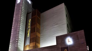 Um hotel com um grande letreiro de 'Grande Abertura', fachada moderna e entrada visível.