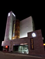 Un hotel con un llamativo letrero de 'Gran Inauguración', una fachada moderna y una entrada visible.