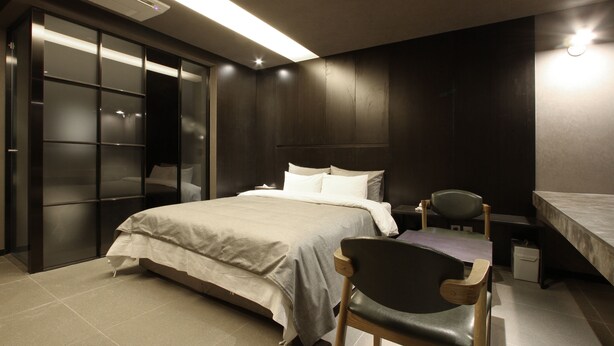 Quarto moderno com cama, cadeira, escrivaninha e armário.