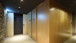 Um corredor com painéis de madeira, piso ladrilhado e uma porta com a inscrição