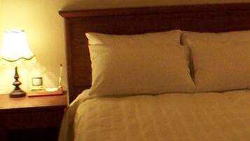 A neatly made bed with white linens and a wooden headboard.