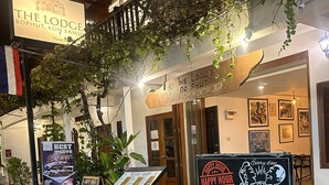 A cozy outdoor seating area with a sign for 'The Lodge' and a menu board advertising beer and cocktails. - The Lodge (Koh Samui)