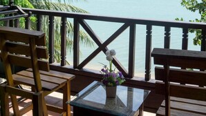A wooden deck with a glass table and chairs overlooking a calm sea with boats. - The Lodge (Koh Samui)