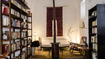 A cozy room with a fireplace, bookshelves, a sofa, and a rocking chair.
