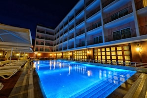 A hotel pool area with a large pool, sun loungers, and a multi-story building with balconies. - Grand Yazici Club Turban (Marmaris)