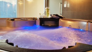 A hot tub with a glass filled with a beverage and a towel on the edge. - The Frames (Paringa)