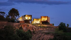 A modern house with two visible rooms, situated on a hill overlooking a body of water. - The Frames (Paringa)