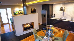 A modern kitchen with a built-in stove, a refrigerator, and a dining area with a table and chairs. - The Frames (Paringa)
