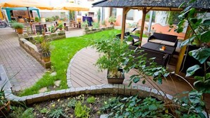 Een terras met een houten dek, een barbecue en potplanten.