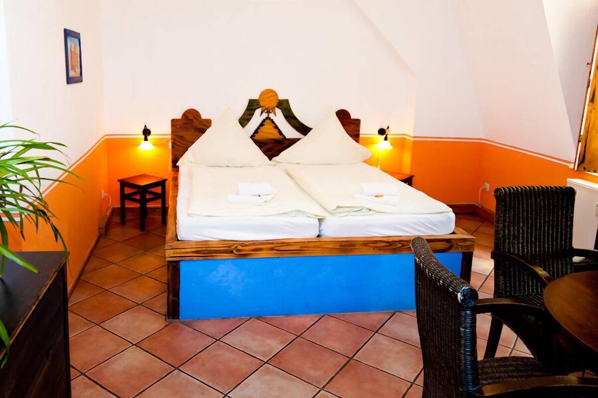 Een kamer met een bed, twee nachtkastjes, een stoel en een tafeltje.