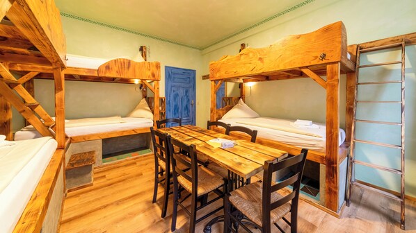 A rustic cabin-style room with two bunk beds, a wooden dining table, and chairs. - Gästehaus Mezcalero B & B (Dresden)