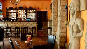 Een restaurantinterieur met stenen muren, houten tafels en een bar.