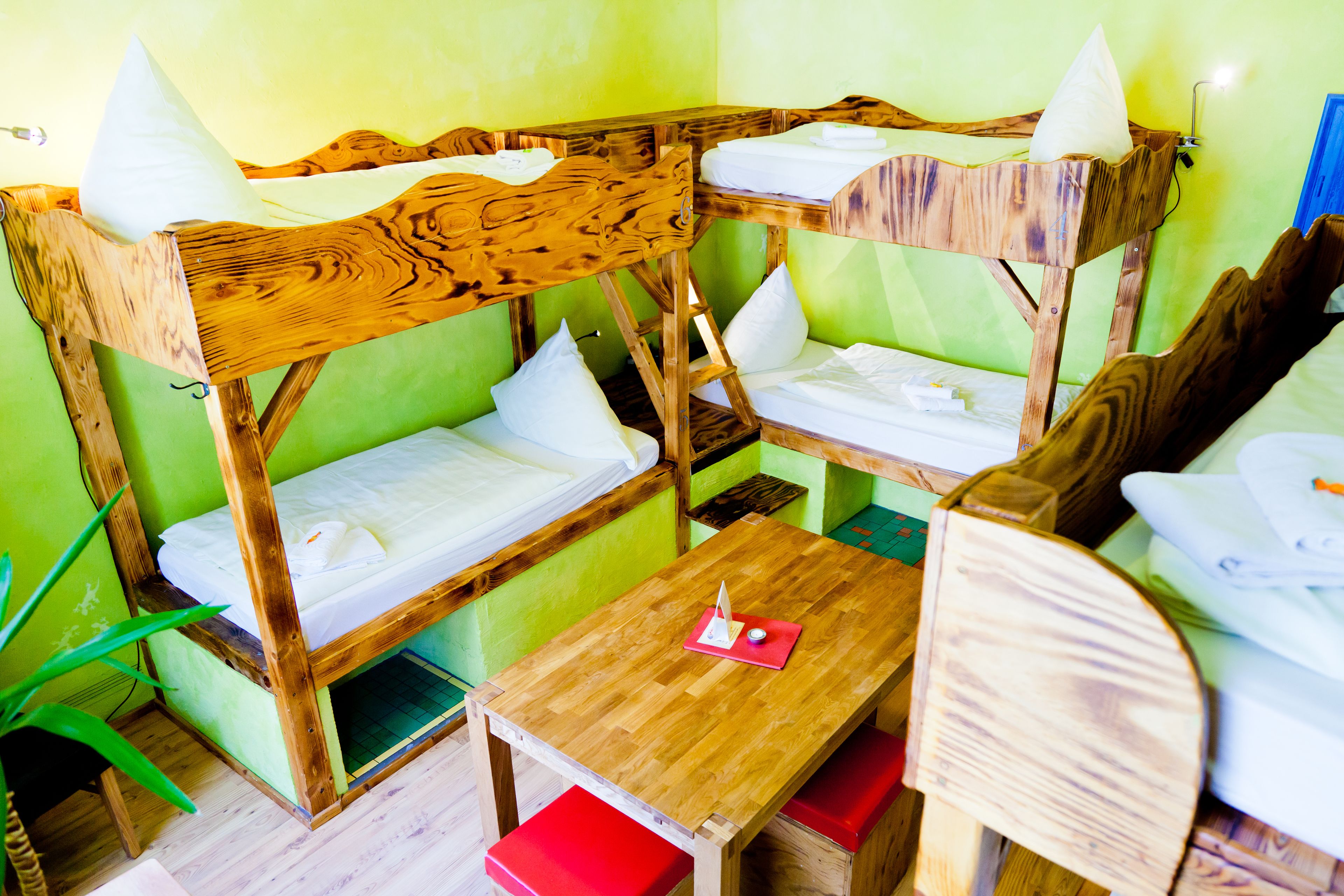 Una habitación con literas, una mesita pequeña y un banco rojo.