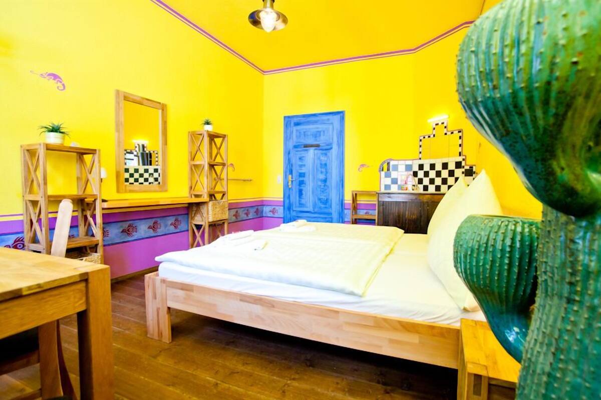 Een kamer met een bed, houten meubels, een blauwe deur en een cactus decoratie.
