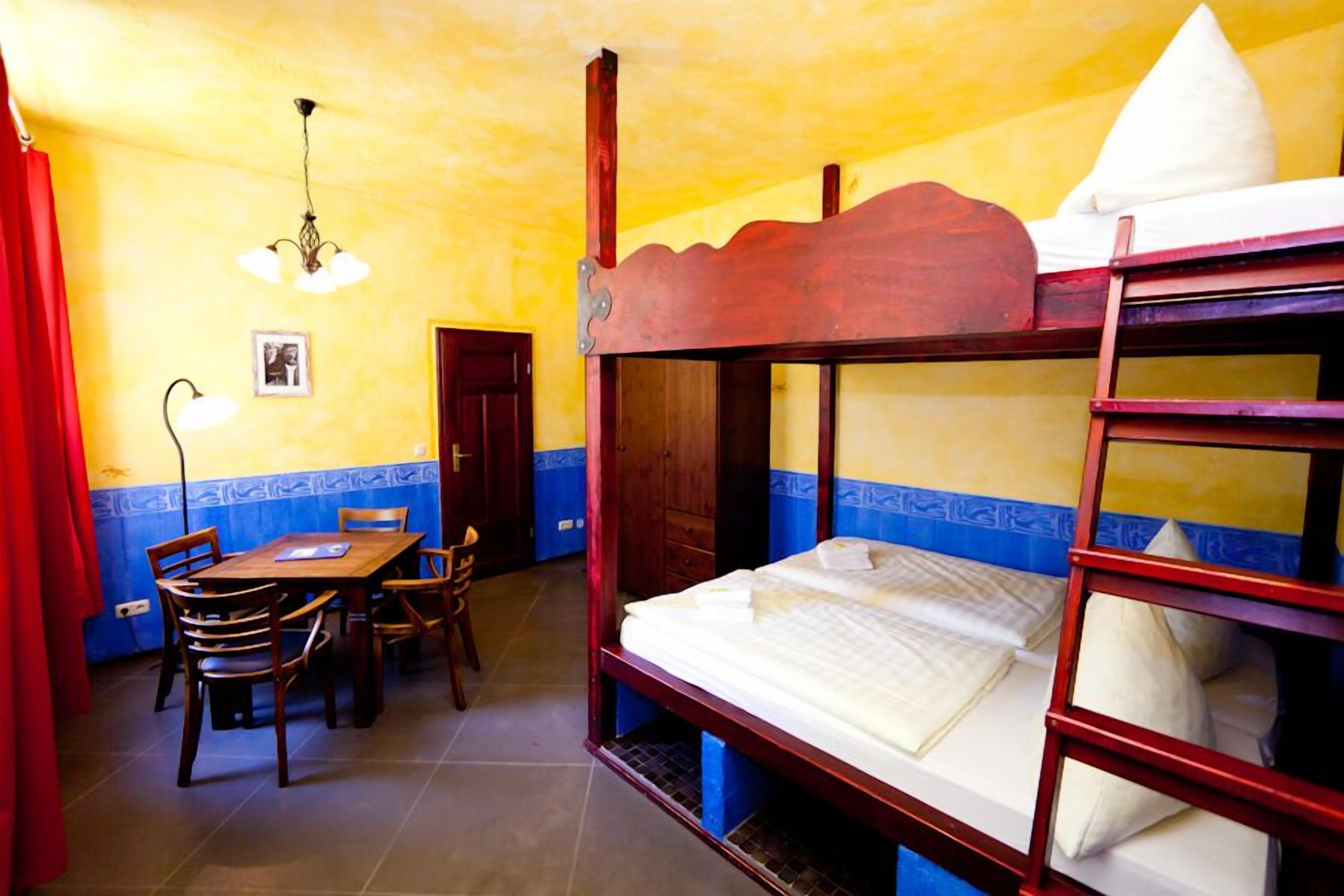 A room with bunk beds, a dining table with chairs, and a chandelier.