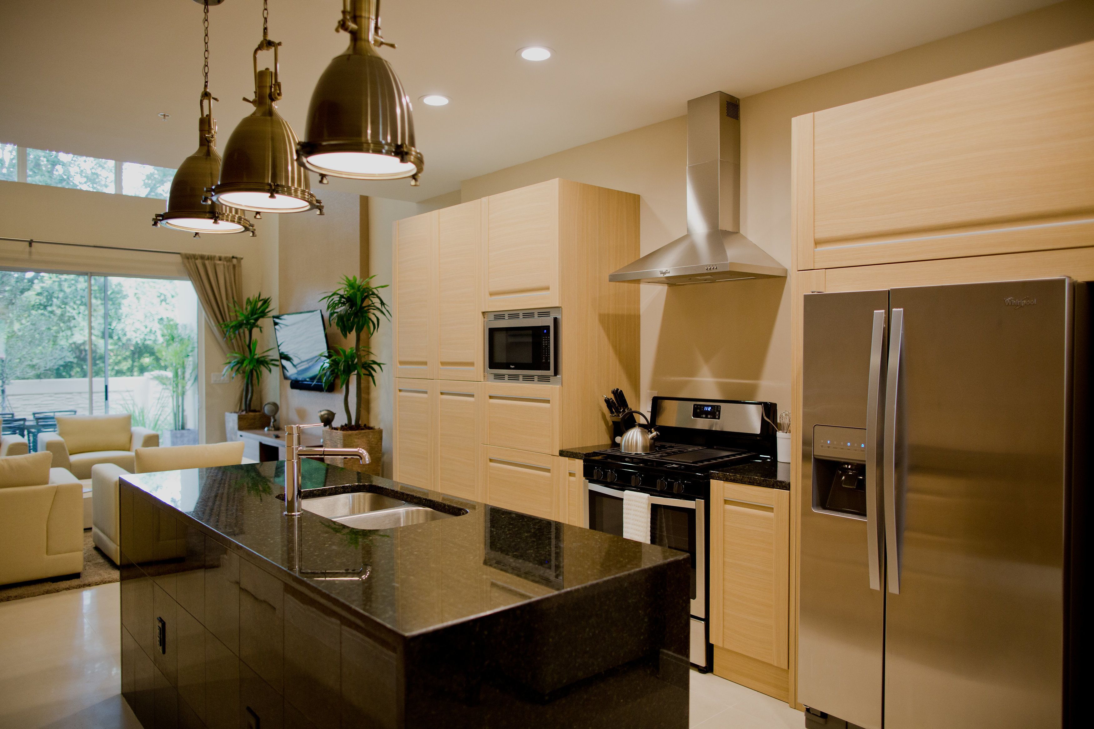 A modern kitchen with a central island, stainless steel appliances, and pendant lighting.