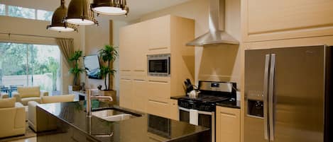 A modern kitchen with a central island, stainless steel appliances, and pendant lighting.