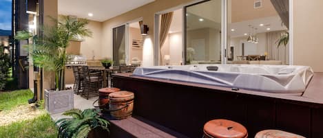 Un área de bar al aire libre moderna con terraza de madera, jacuzzi y barriles rústicos.