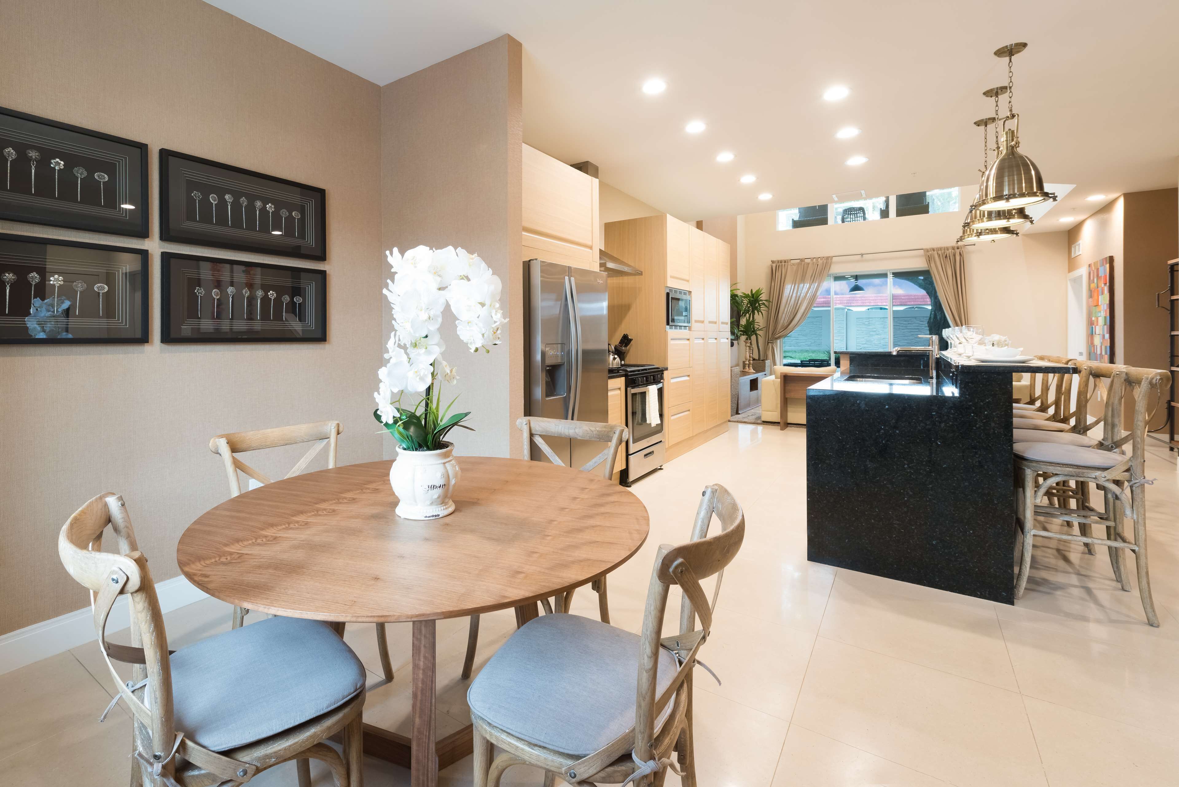 A modern kitchen with a central island, wooden chairs, and a dining table.