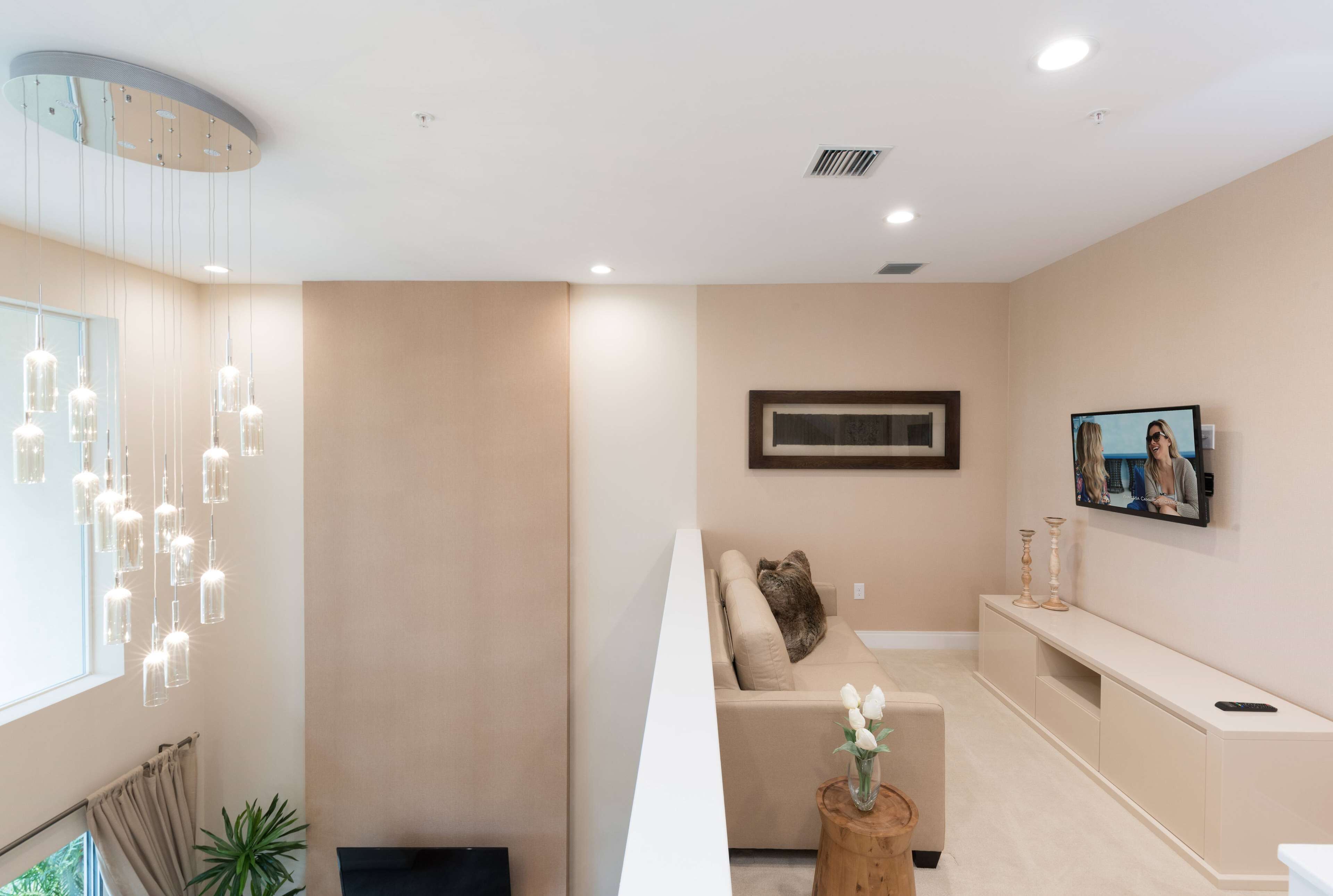 A modern living room with a sofa, a TV, and a wooden side table with a vase.