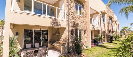 A two-story building with a balcony, outdoor seating area, and a stone facade.