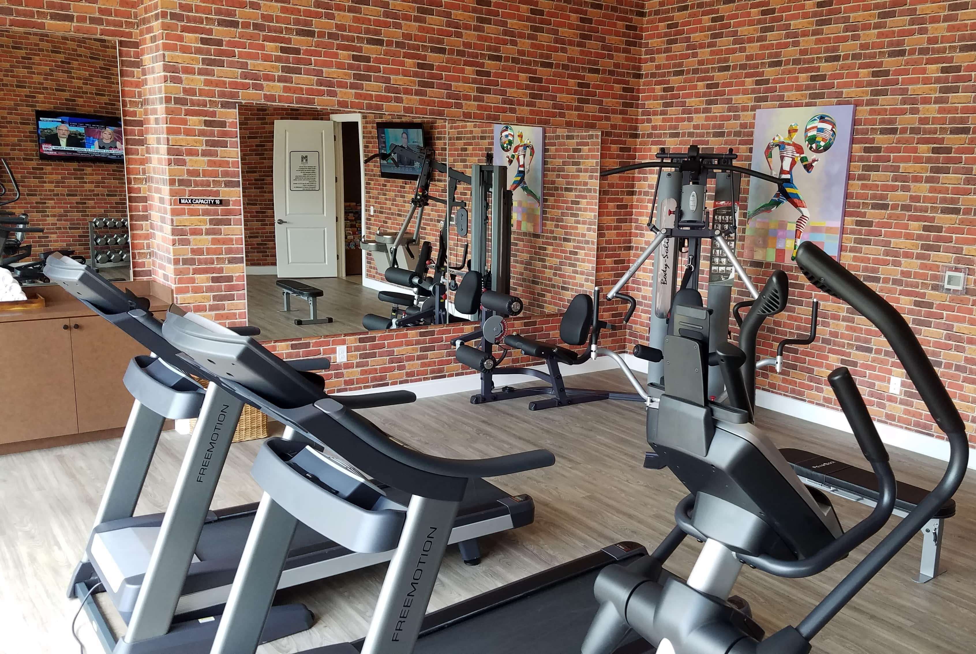 A gym with treadmills, weight machines, and a mirror.
