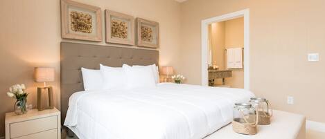 Un dormitorio ordenado con una cama grande, mesitas de noche y elementos decorativos.