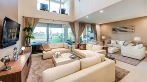 A spacious living room with a large TV, comfortable seating, and a view of the outdoors. - Magic Village Yards, Trademark Collection by Wyndham (Kissimmee)