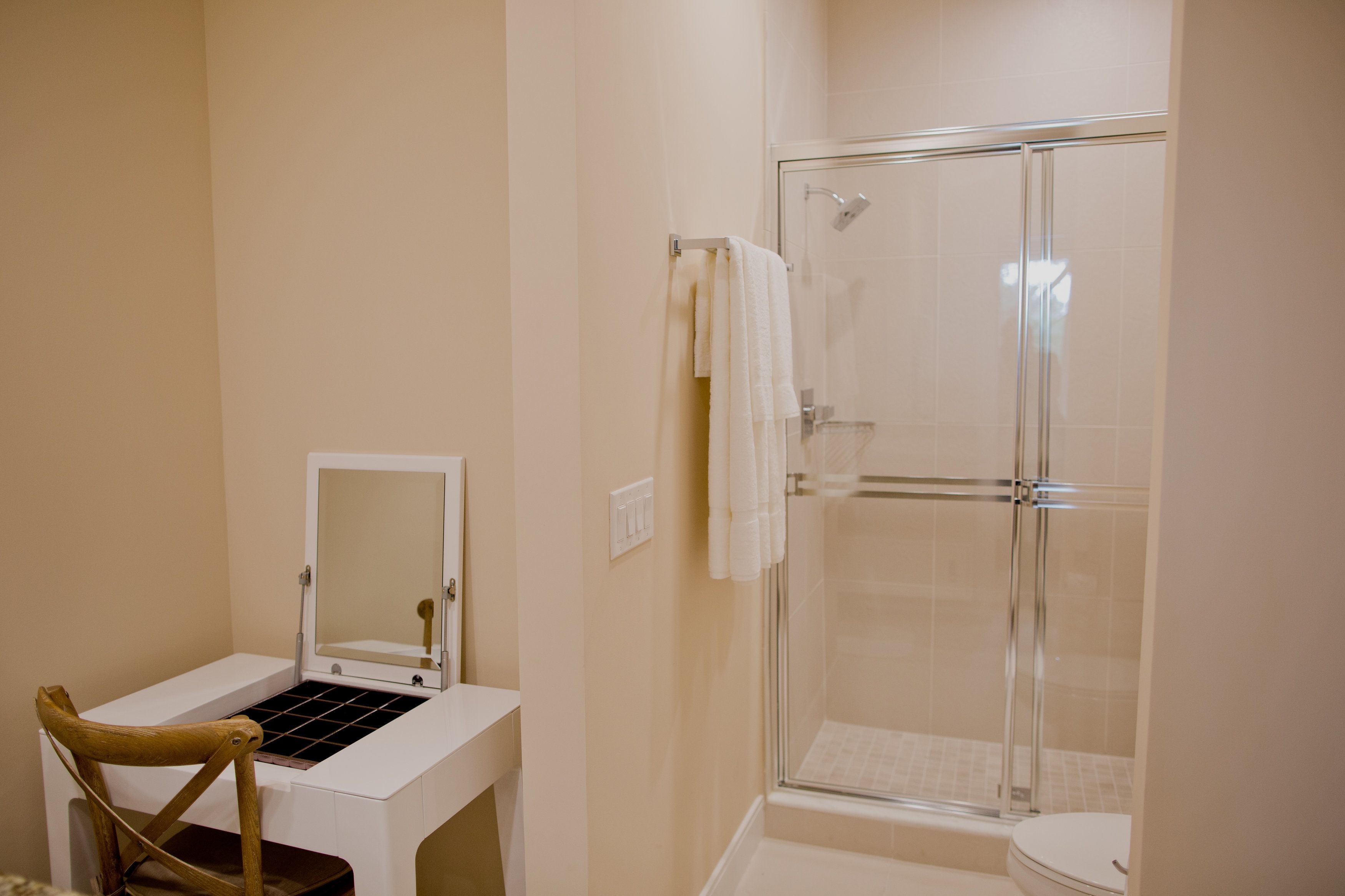 A bathroom with a white vanity, a mirror, a shower with a glass door, and a toilet.