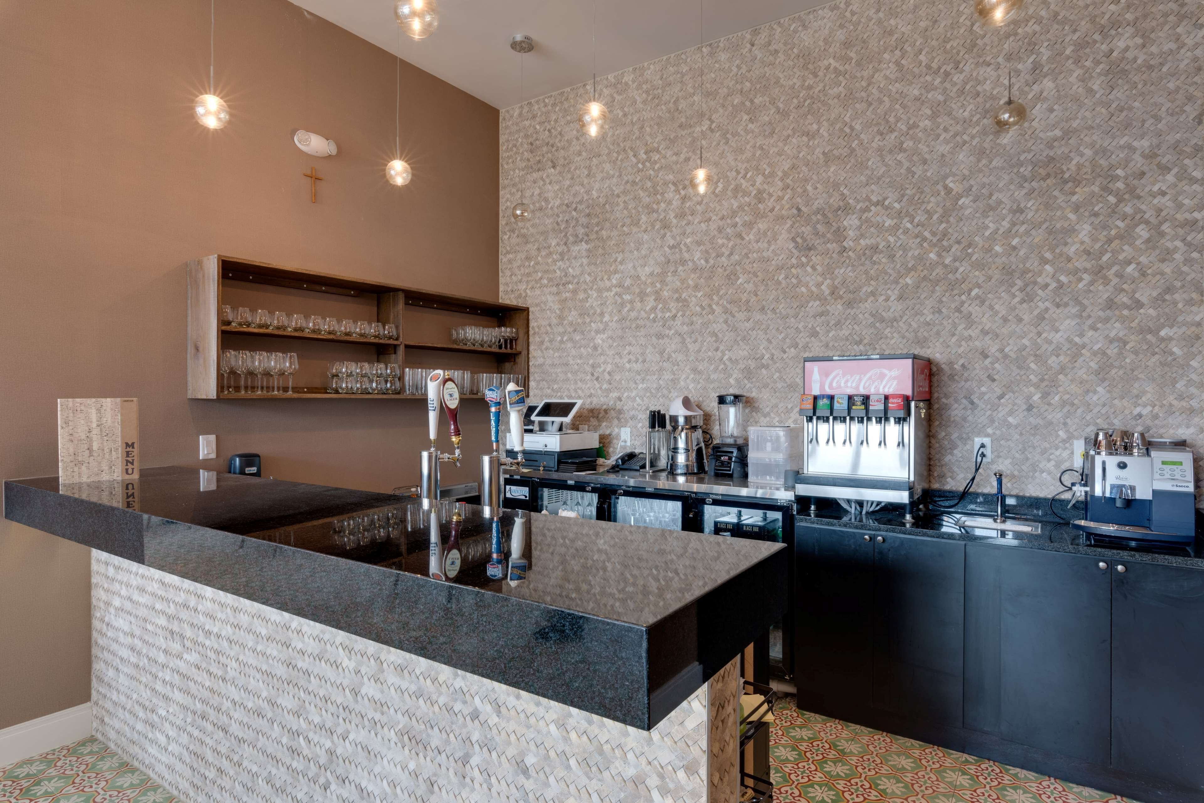 A modern bar area with a granite countertop, bar stools, a coffee machine, and a Coca-Cola dispenser.