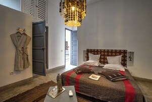 Un dormitorio moderno con una cama, una bata colgada en la pared, una araña y vistas al exterior.