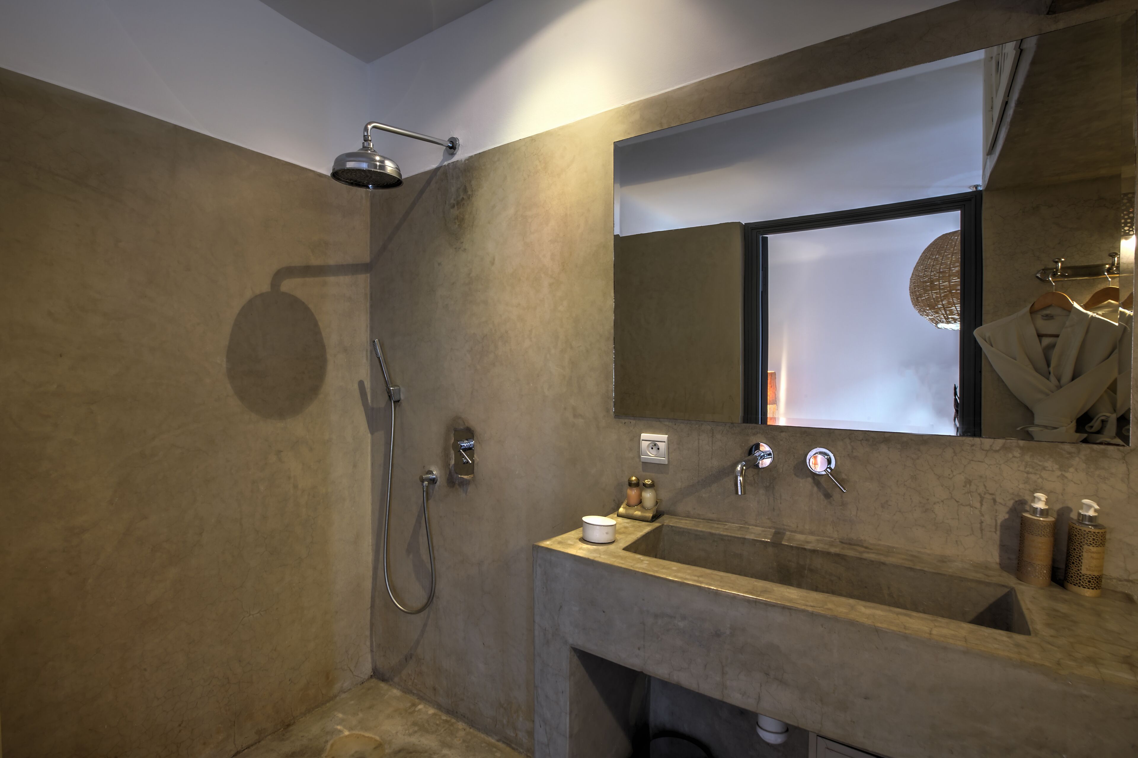 A modern bathroom with a large sink, a shower, and a mirror.
