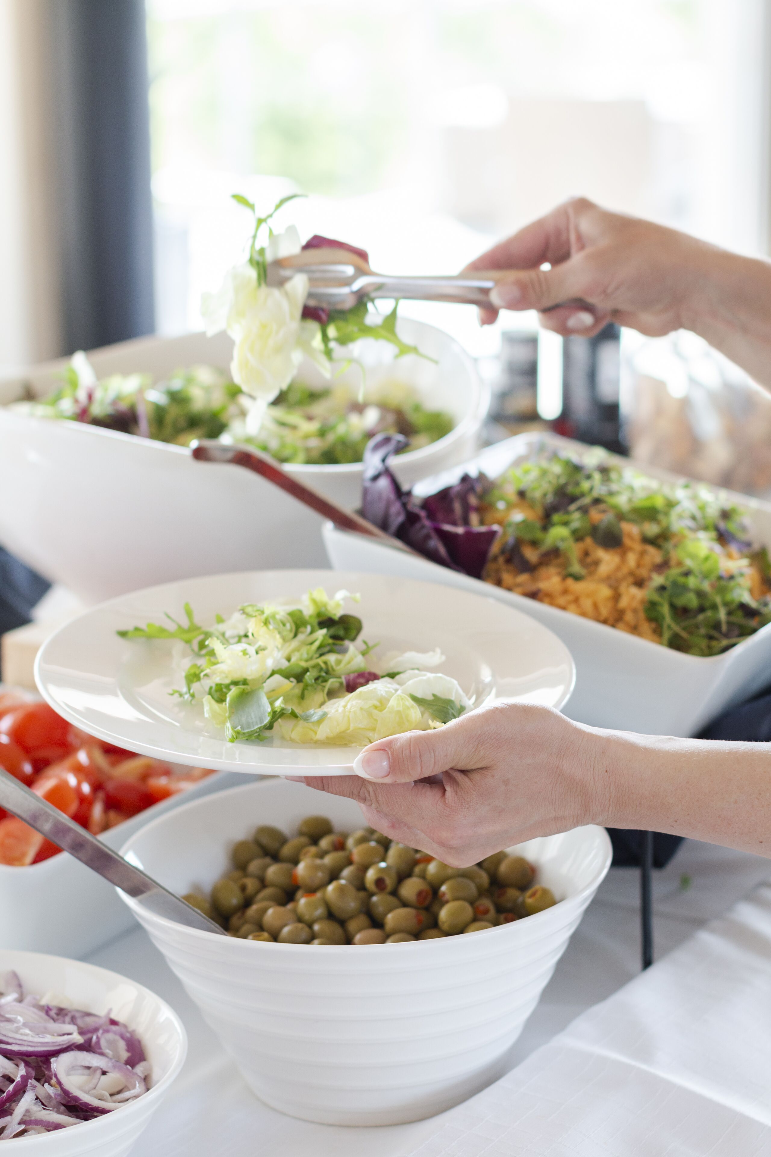 Un tavolo da buffet con diversi piatti, tra cui insalate, una ciotola di olive e un piatto con cipolle affettate.