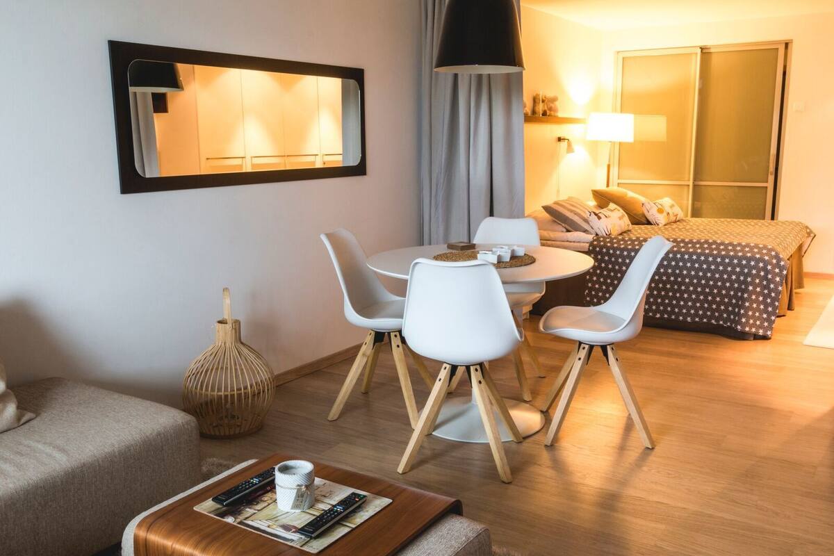 Une chambre d’hôtel moderne comprenant un coin repas, un lit avec une couette à motifs étoilés, un grand miroir et une lampe.