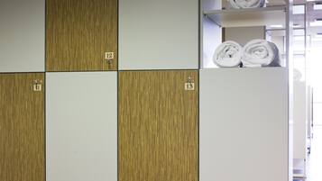 Habitación de hotel con pared de paneles de madera, un zapatero y un jarrón de vidrio con flores.