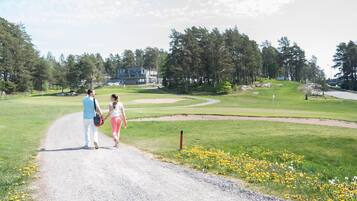 A gravel path leading to a golf course with a building in the background.