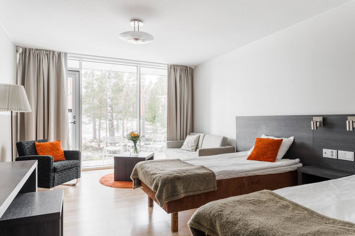 Une chambre d’hôtel moderne dotée d’une grande fenêtre, d’un canapé, d’un lit et d’un bureau.