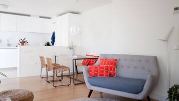 Una sala de estar moderna con un sofá gris, almohadas rojas y un comedor con una mesa y sillas.