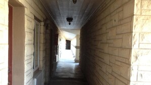 A narrow corridor with stone walls and a concrete floor, leading to a staircase at the end. - Executive Inn (Snyder)