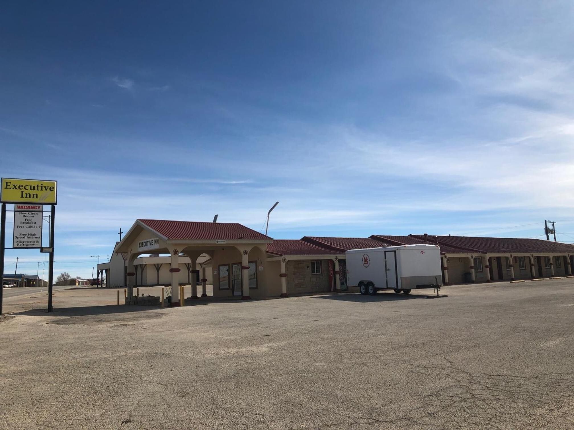 A motel with a sign indicating vacancies and amenities like new clean rooms, breakfast, free cable TV, high-speed internet, and a refrigerator.