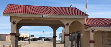 A gas station with a red roof and beige walls, featuring a '9 FT CLEARANCE' sign.