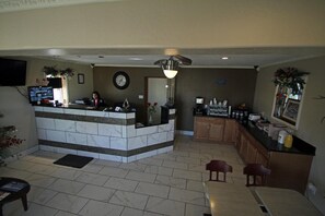 A spacious kitchen with a marble island, wooden cabinets, and a dining area with two chairs.